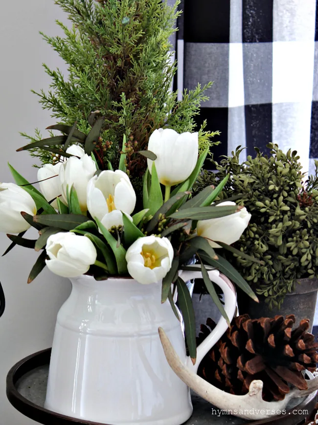 Winter vignette with white tulips, mini cypress, pinecones, antlers and more