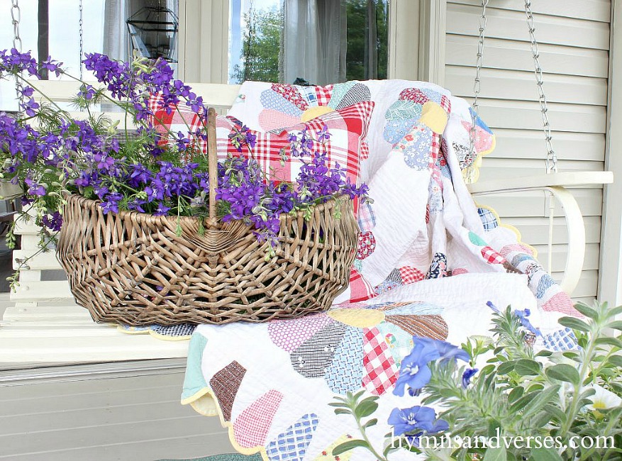 Vintage quilt on porch swing and basket of purple larkspur flowers - Hymns and Verses