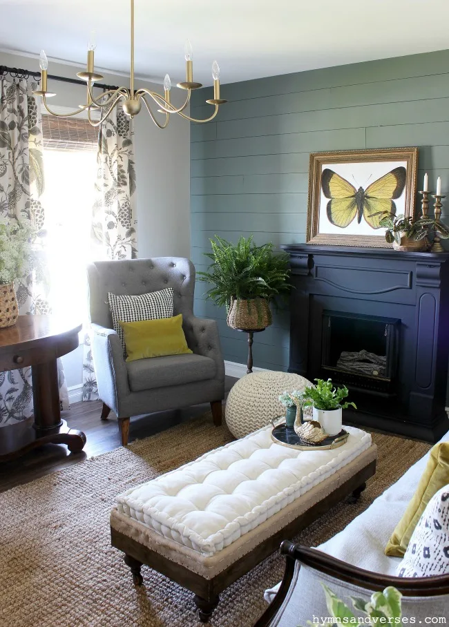 Vintage style summer living room with moody green accent wall and black fireplace mantel - Hymns and Verses Blog