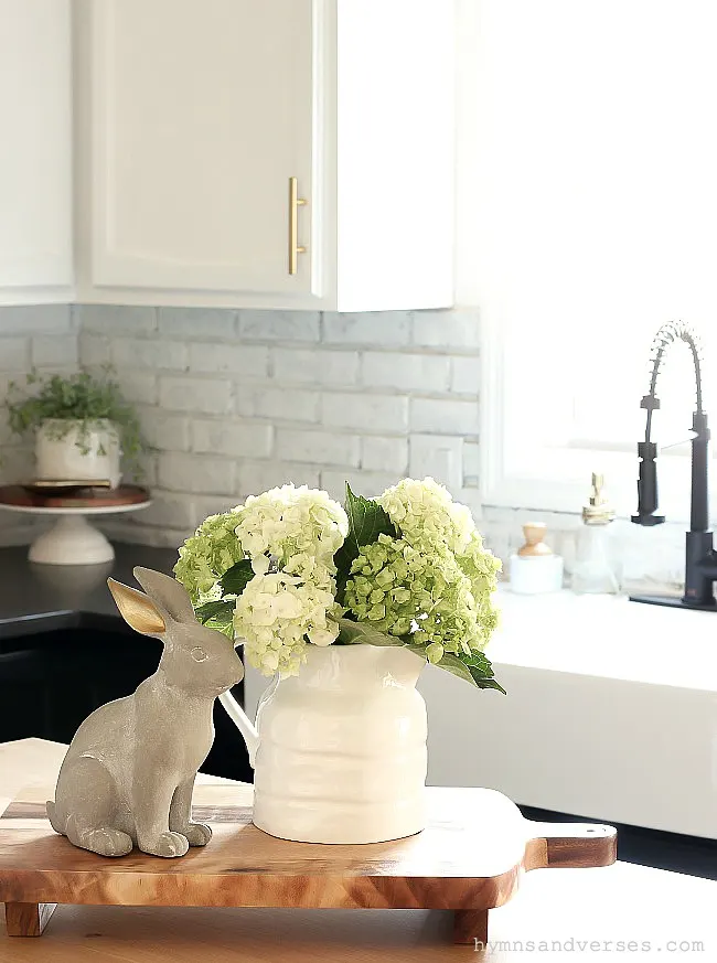 Black and white kitchen with painted brick backsplash styled for spring