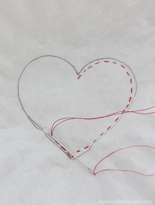 Red thread running stitch around the inside perimeter of a heart shape.