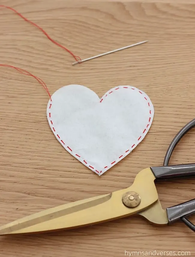 Red stitched heart with opening at the left top.  Scissors shown for cutting the shape.