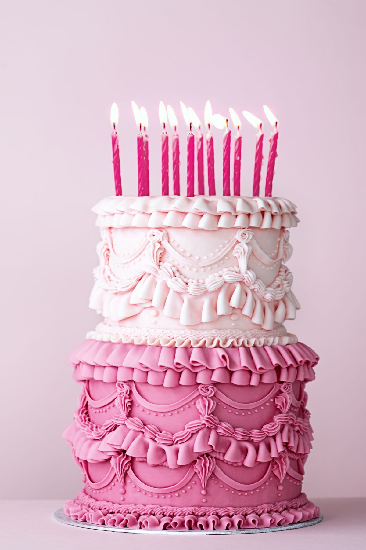two tiered pink decorated cake with pink candles