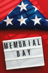 folded American flag and sign that says Memorial Day on red background